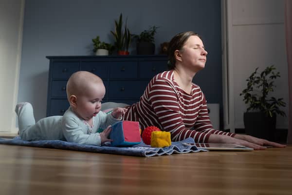 Mother with her baby on yoga mat at home