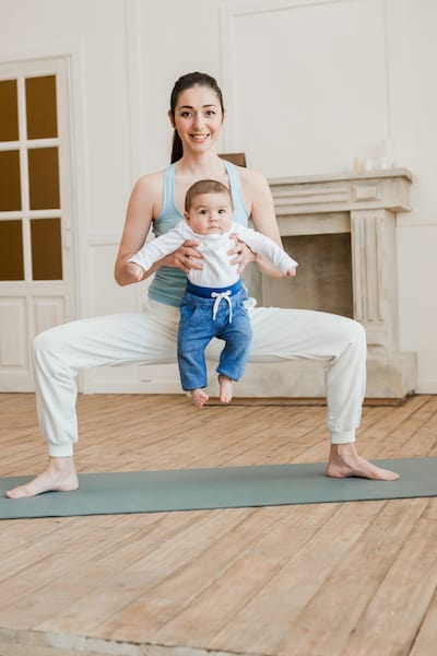 Mother with her child standing in yoga position on yoga mat at home