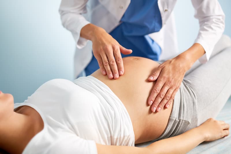 Young pregnant woman having examination of her belly