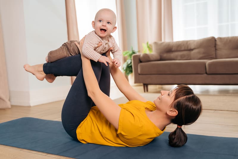 Postnatal recovery. Mom practicing pilates with her infant baby at home