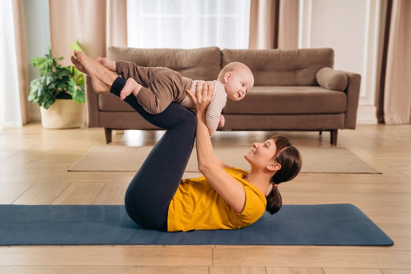 Postpartum recovery. Mommy practicing pilates with her baby