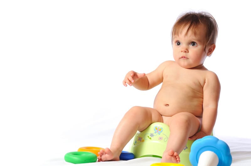 A baby sits on a potty chair