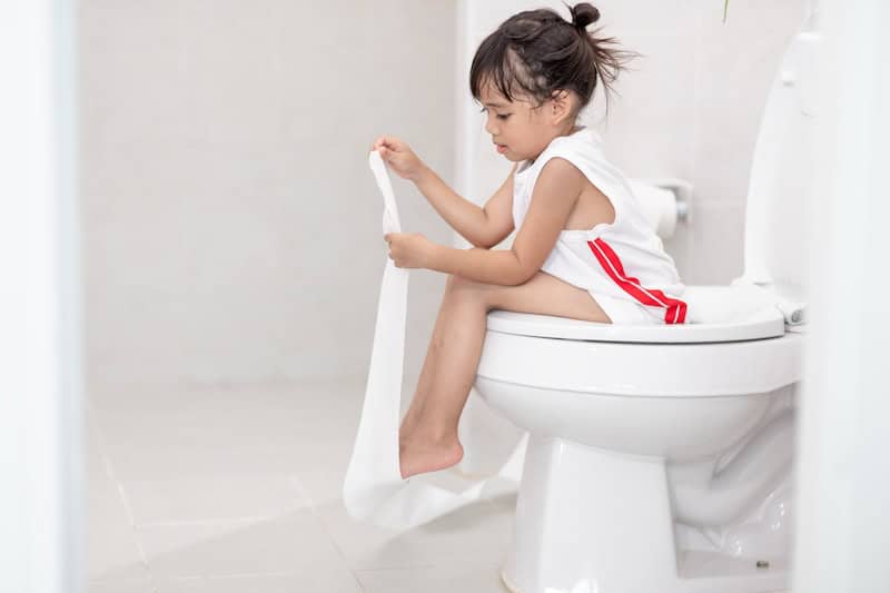 A little girl sitting on adult toilet