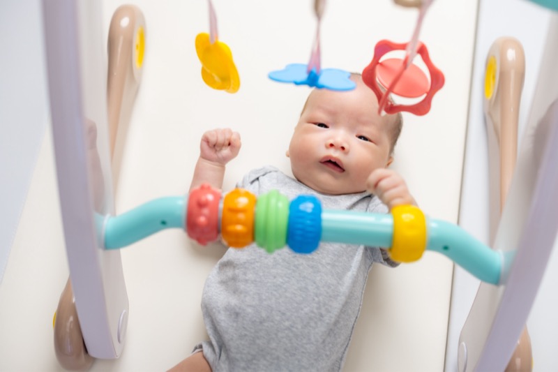 Newborn baby lying down and looking at the hanging toys